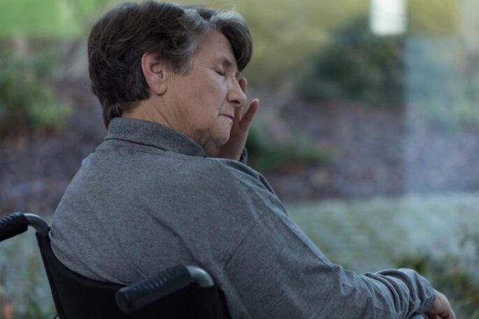 An older woman sits sadly in a wheelchair