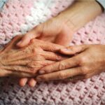 an older person's hand holds a younger person's hands