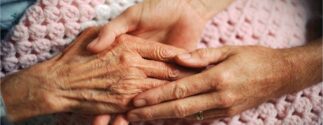 an older person's hand holds a younger person's hands