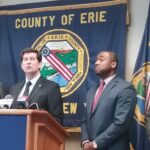 A group of Erie County officials stand at a podium during a press conference