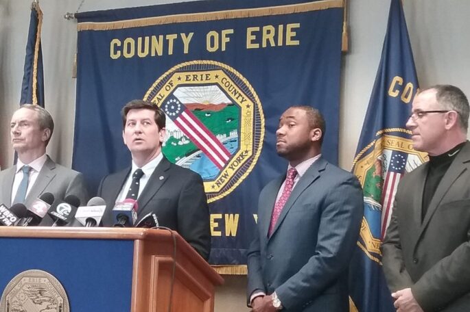 A group of Erie County officials stand at a podium during a press conference