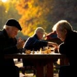 Older men play chess outside in a park
