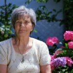 an older woman sits pensively outside