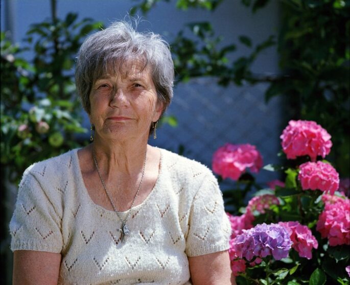 an older woman sits pensively outside