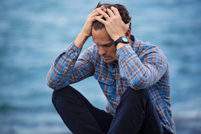 A man sits holding his head in his hands