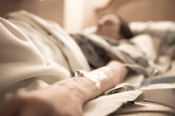An old woman lies in a hospital bed