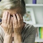 An old woman holds her head in her hands