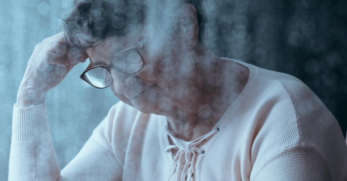 elderly woman holding her head looking sad