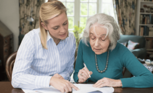 A nursing home attorney helps an older woman fill out paperwork at a table.