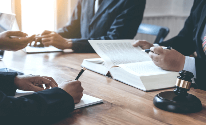 Lawyers sit at a desk with books and documents to negotiate a nursing home lawsuit.