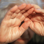 an older woman cowers in fear and covers her face with her hands