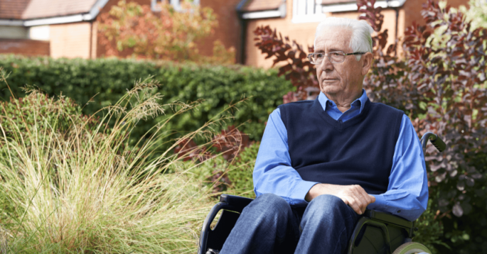 a sad older man sits in a wheelchair