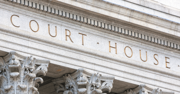 A closeup shot of a grey stone court house building.