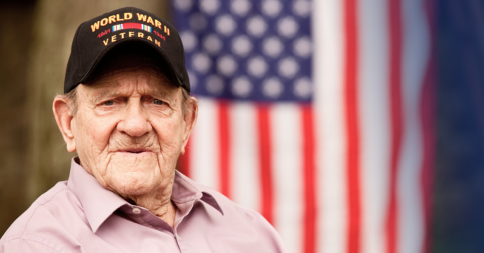 Senior veteran sits in front of flag