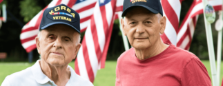 two veterans stand in front of flags