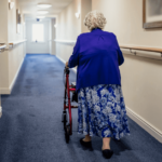 Nursing home resident walks down empty hall