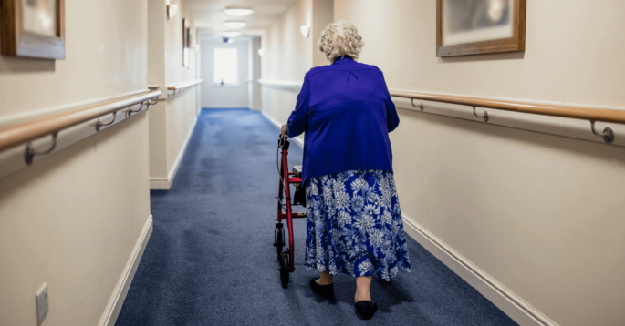 Nursing home resident walks down empty hall