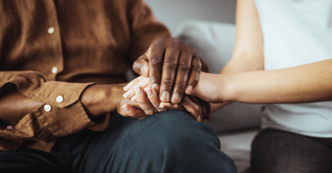 Two people holding hands in comfort