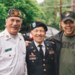 Three older male veterans smile together outside