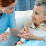 Nurse administering medication to an elderly patient