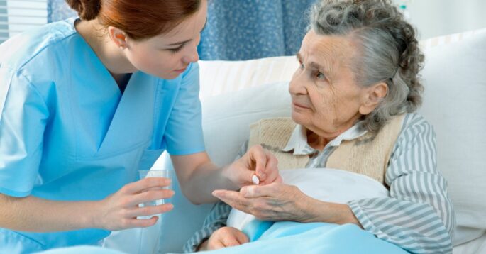 Nurse administering medication to an elderly patient